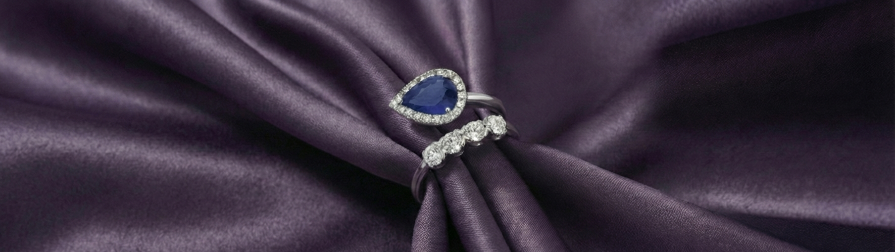 Two rings with gemstones on a purple fabric background